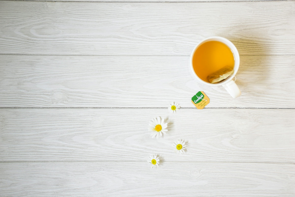 a cup of tea next to some daisies