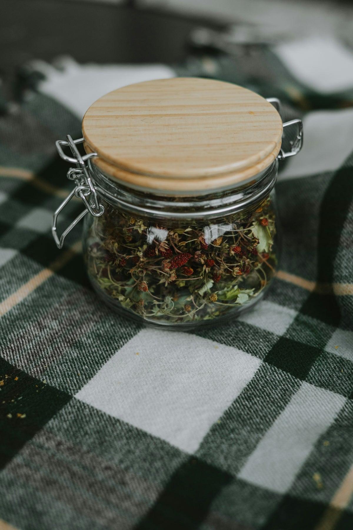a glass jar filled with herbs sitting on top of a table